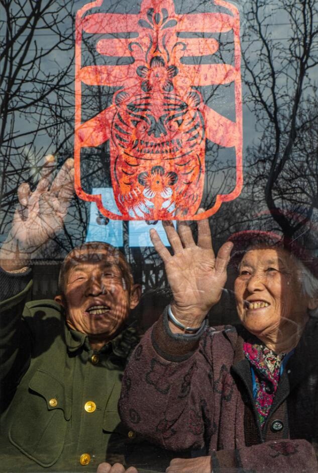 臘月里，霍州市師莊鄉(xiāng)馮南垣村村民師榮光(左)在災(zāi)后重建的新家里貼窗花。(霍州市委宣傳部供圖)