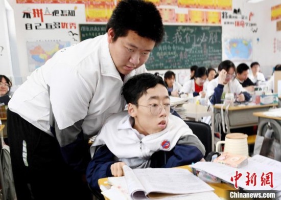 朱金祥(左)把鐘華強放到課堂座位上后，都要把他擺正好，確認安全后才回到自己的座位上。 卓忠偉 攝