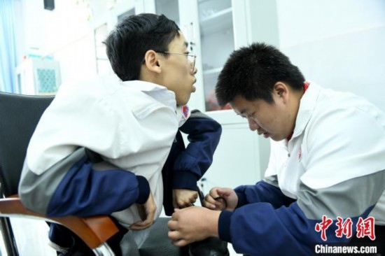 江西省南康中學北校區(qū)的高三學生朱金祥(右)正在給鐘華強(左)系好鞋帶。 卓忠偉 攝