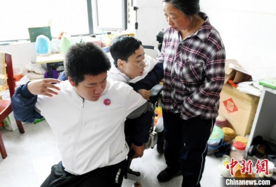 江西省南康中學北校區(qū)的高三學生朱金祥(左)來到學校給鐘華強母子安排的公寓，準備背他去課堂上課。 卓忠偉 攝