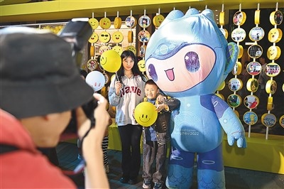 5月7日，在浙江省杭州市湖濱步行街“3D笑臉墻”前，攝影師為游客與杭州亞運(yùn)會(huì)吉祥物之一“宸宸”拍攝合影。