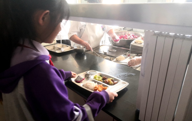 伊金霍洛旗第一小學(xué)學(xué)生正在打飯，今天的飯菜是三菜一湯外加水果，學(xué)生可以多次盛取，吃飽為止。人民網(wǎng)記者 孫博洋攝