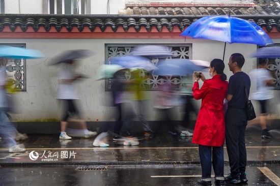 6月7日，在浙江省2023年普通高校招生考試鎮(zhèn)海中學(xué)考點，家長冒雨目送子女進入考場。人民網(wǎng) 章勇濤攝