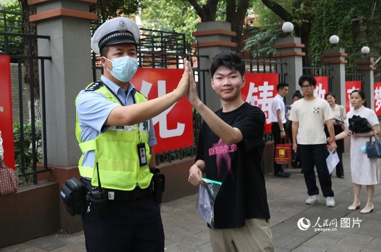 6月7日8時許，武漢中學(xué)考點門口，交警在維護秩序，并?？忌鸢耦}名。人民網(wǎng)記者 肖璐欣攝