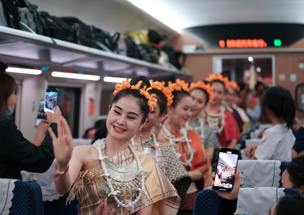 2023年4月13日，老撾工作人員在D887次國際旅客列車上表演。當日，中老鐵路從中國昆明南站、老撾萬象站雙向?qū)﹂_D887次和D888次國際旅客列車，兩地乘火車可當日通達。中老鐵路是高質(zhì)量共建“一帶一路”的標志性工程。新華社記者 邢廣利 攝