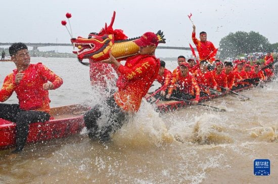 6月22日，在湖南省岳陽市湘陰縣湘江臨資口水域，參加龍舟賽的隊員接“龍頭”下水。