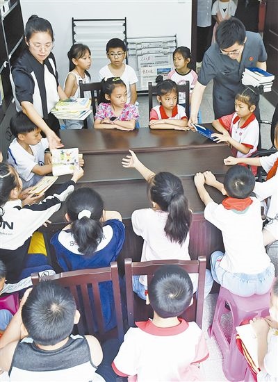  圖④：法院干警為留守兒童發(fā)放暑假讀物。