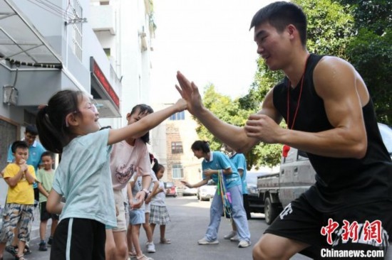 圖為大學(xué)生志愿者在組織孩子們參加體育健身活動。廖光福 攝
