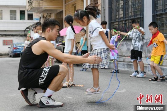 圖為大學(xué)生志愿者在教孩子們學(xué)跳繩。廖光福 攝