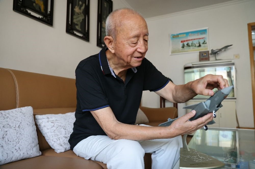 ↑2023年7月24日，新中國第一代飛行員陶偉在家中擦拭殲-20飛機(jī)模型。新華社發(fā)（張瑞 攝）