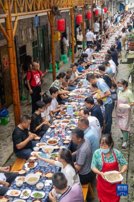 7月29日，在重慶市綦江區(qū)安穩(wěn)鎮(zhèn)，人們在“苗家伏羊節(jié)”上吃長桌宴。新華社記者 唐奕 攝