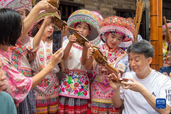 7月29日，在重慶市綦江區(qū)安穩(wěn)鎮(zhèn)，當?shù)鼐用裨凇懊缂曳蚬?jié)”上用傳統(tǒng)習(xí)俗向游客表達祝福。新華社記者 唐奕 攝