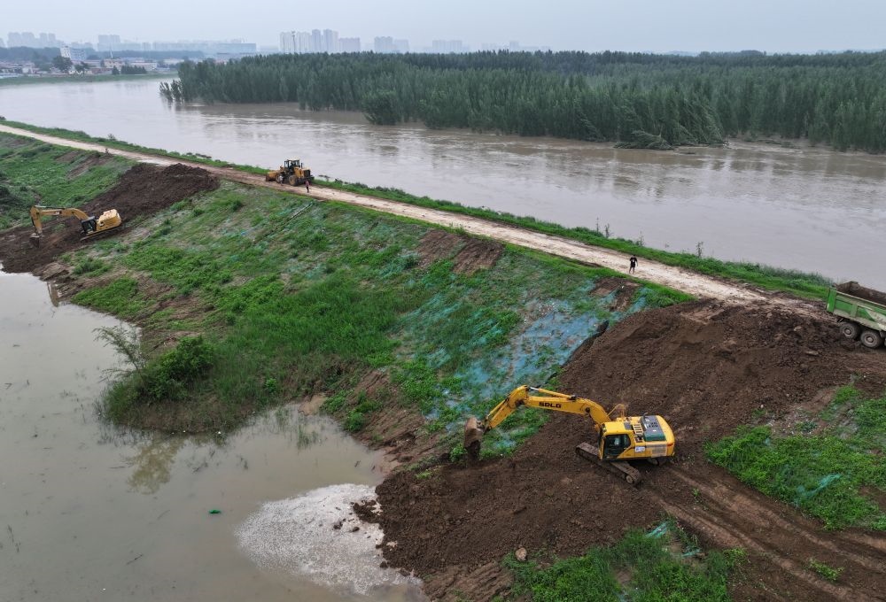 工人操作機械在白溝河左堤白溝新城高橋村段進行除險加固作業(yè)（8月4日攝，無人機照片）。新華社記者 朱旭東 攝