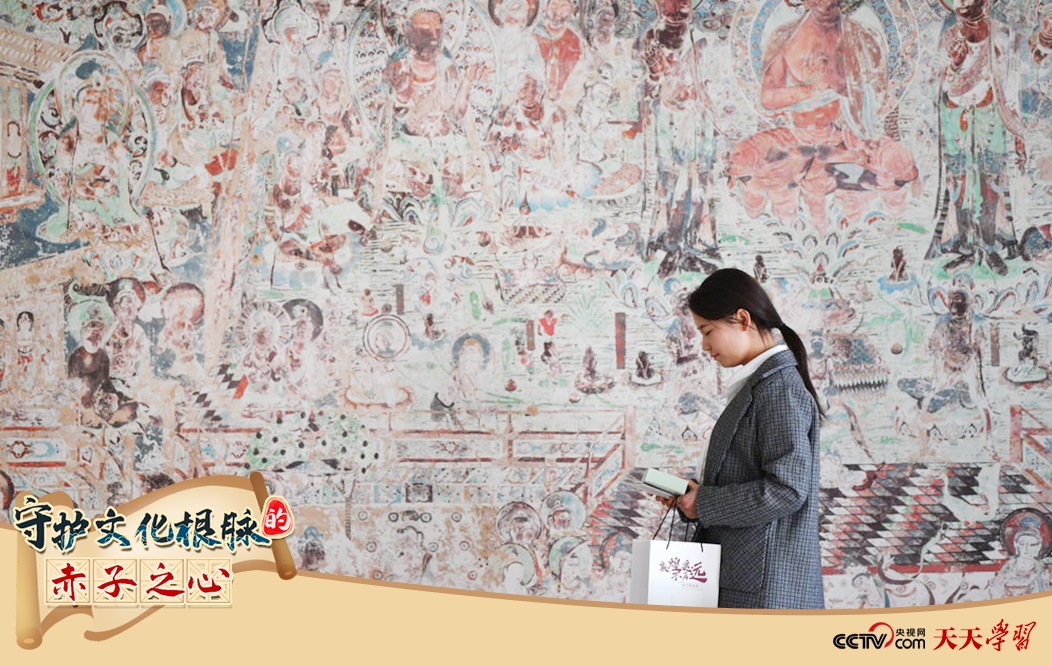 2023年4月25日，敦煌研究院文物數(shù)字化保護團隊創(chuàng)意營銷人員廖雪婷從一幅高保真復(fù)制壁畫前走過。