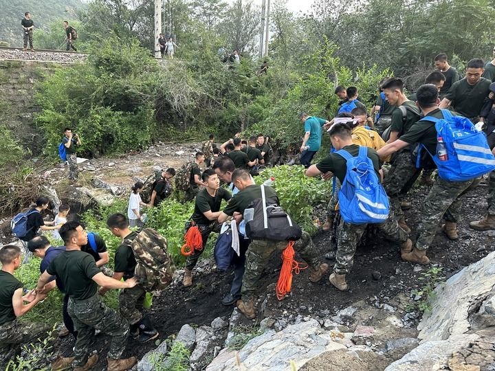 8月2日，Z180次受困列車的旅客在武警北京總隊機動第三支隊官兵的幫助下徒步前往轉運客車（手機照片）。新華社記者 王艷剛 攝