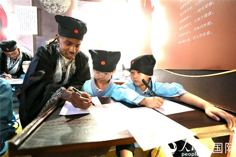 圖為選手與同學們一起寫書法。人民網(wǎng) 盧鵬宇攝