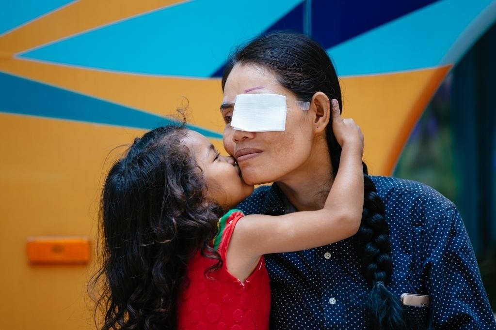 2019年3月15日，在柬埔寨磅湛省醫(yī)院，即將接受白內(nèi)障手術(shù)的患者孫美樂接受女兒的親吻祝福。在接受了中國醫(yī)療隊的白內(nèi)障義診手術(shù)后，她的視力逐步恢復(fù)，生活有了新的光明和希望。