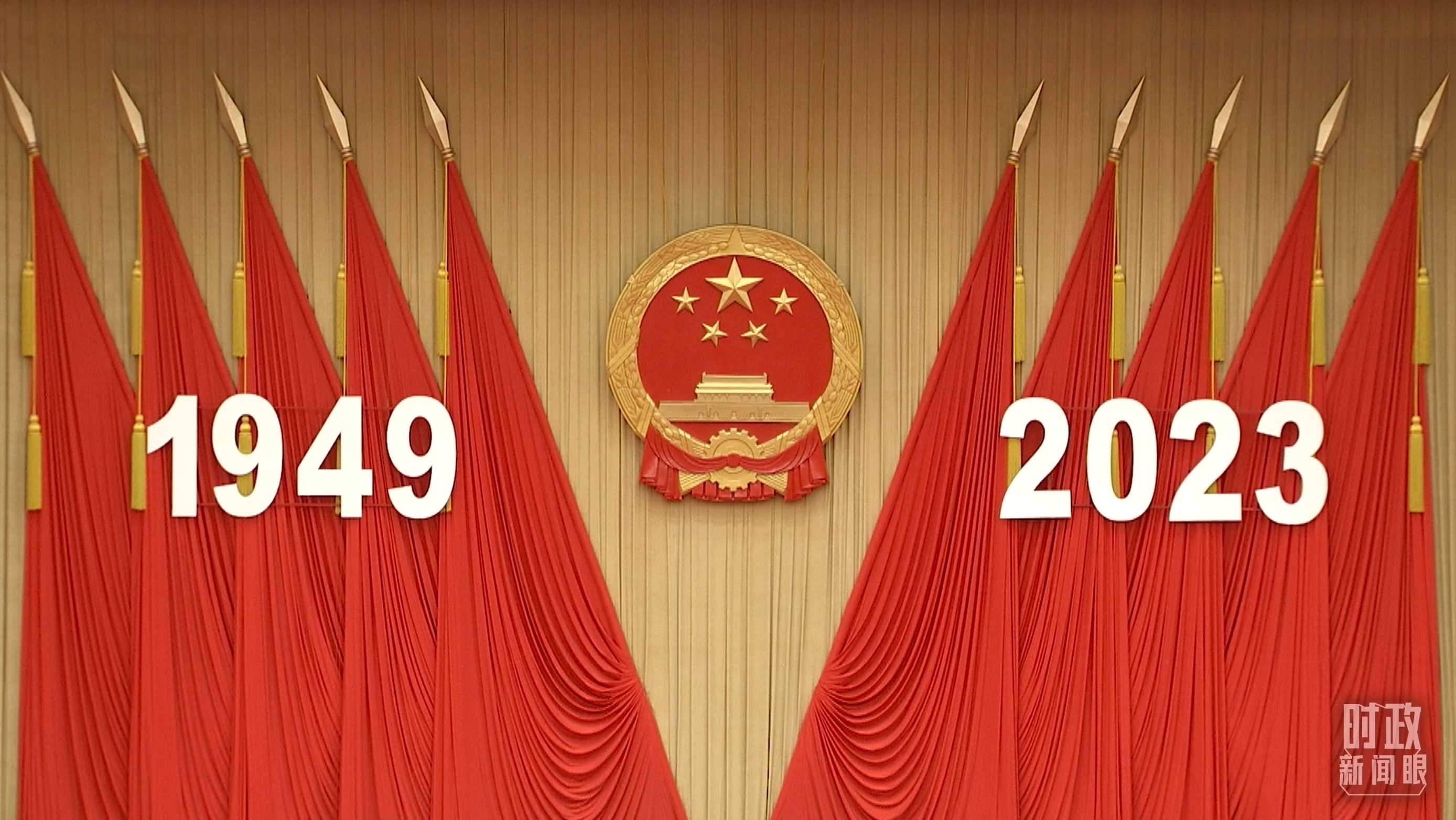 △人民大會堂宴會廳內，主席臺上方高懸著莊嚴的國徽，“1949－2023”大字年號在鮮艷的紅旗映襯下格外醒目。