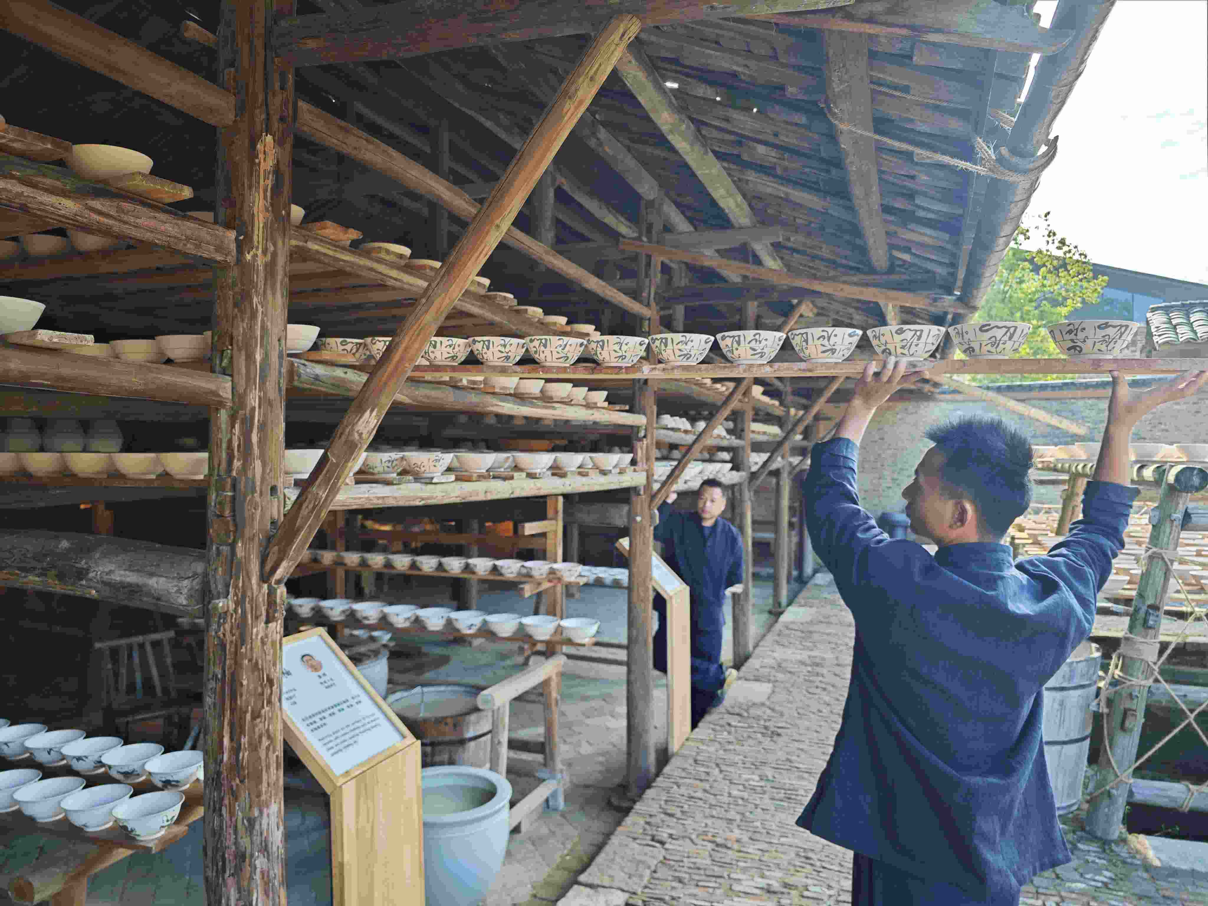 △陶陽里歷史文化街區(qū)里，工匠將陶瓷工藝品放到架上晾干。（總臺央視記者彭漢明拍攝）