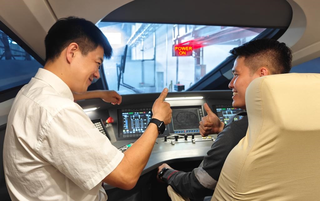 8月25日，在印度尼西亞萬隆的雅萬高鐵德卡魯爾動車所內(nèi)，中國師傅穆振（左）在向印尼火車司機塞蒂亞萬講解動車組出庫前的上電作業(yè)。