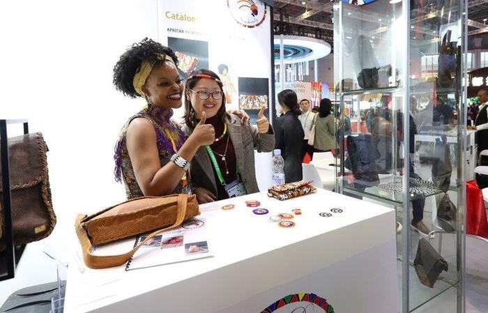 11月6日，一位參觀者（右）在第六屆進(jìn)博會國家展南非展臺試戴傳統(tǒng)首飾。