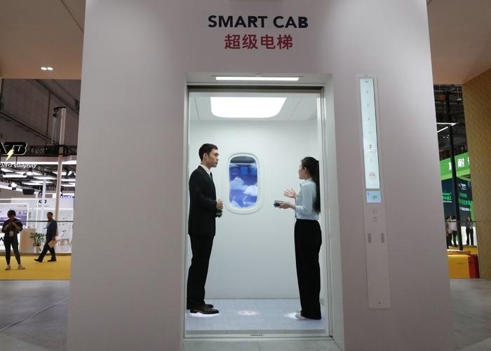 11月5日，工作人員（右）在第六屆進(jìn)博會上向參觀者介紹奧的斯公司全新推出的超級電梯。