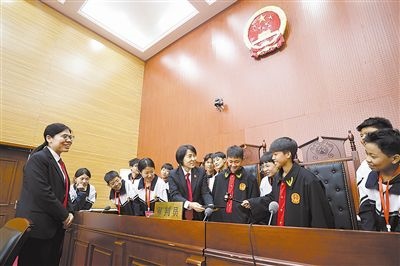圖③：同學(xué)們穿法袍、敲法槌，爭做“小法官”。