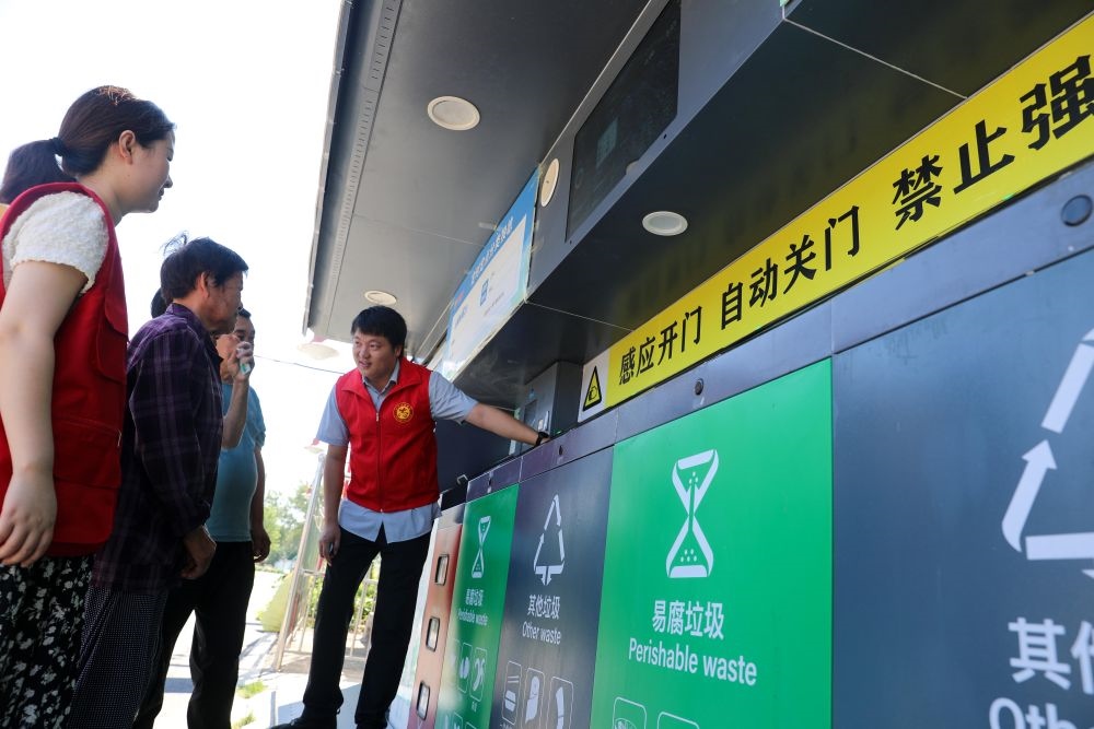 在安徽省合肥市長豐縣莊墓鎮(zhèn)棗林社區(qū)，志愿者指導(dǎo)居民使用智能垃圾分類回收設(shè)備（2023年9月1日攝）。新華社記者 曹力 攝
