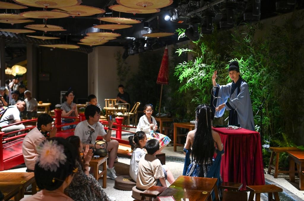 游客在長(zhǎng)安十二時(shí)辰主題街區(qū)觀看唐風(fēng)演藝《大唐曲藝》。新華社記者鄒競(jìng)一 攝