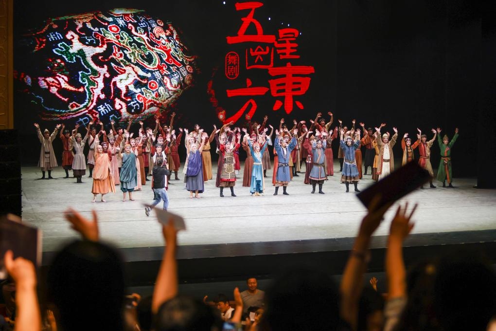 2023年7月31日，新疆和田地區(qū)新玉歌舞團(tuán)在烏魯木齊京劇院演出舞劇《五星出東方》后和觀眾互相揮手致意。這場(chǎng)演出是第六屆中國(guó)新疆國(guó)際民族舞蹈節(jié)的參演劇目之一，曾榮獲國(guó)家“文華獎(jiǎng)”等。新華社記者 郝昭 攝