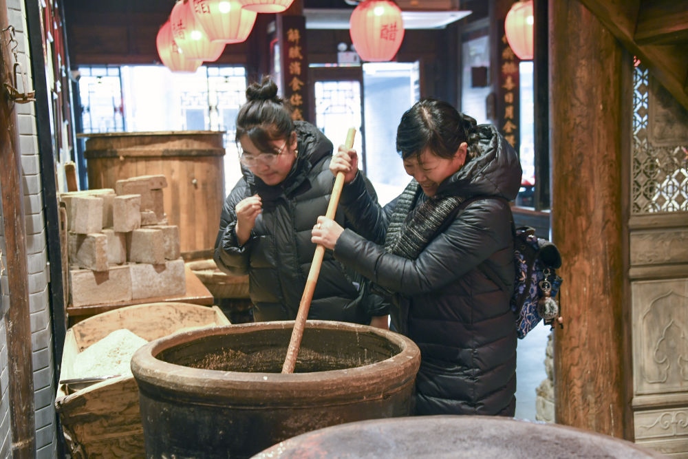 游客在平遙古城東湖老醋坊內(nèi)體驗(yàn)陳醋發(fā)酵打耙（2022年1月28日攝）。新華社發(fā)（梁生仁攝）