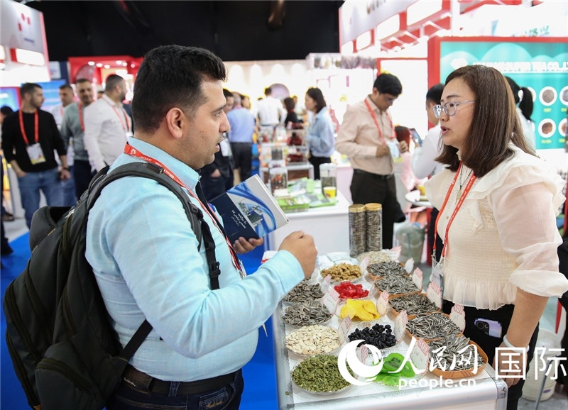 圖為一家中國(guó)干果參展企業(yè)代表與采購商洽談。人民網(wǎng) 塔里克·易卜拉欣攝