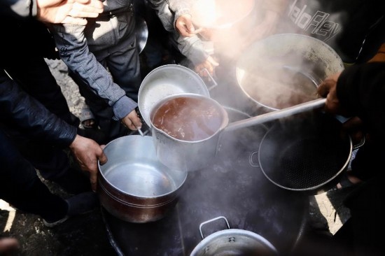 2月27日，在加沙地帶北部的杰巴利耶難民營，人們領(lǐng)取食物。新華社發(fā)（穆罕默德·阿里攝）