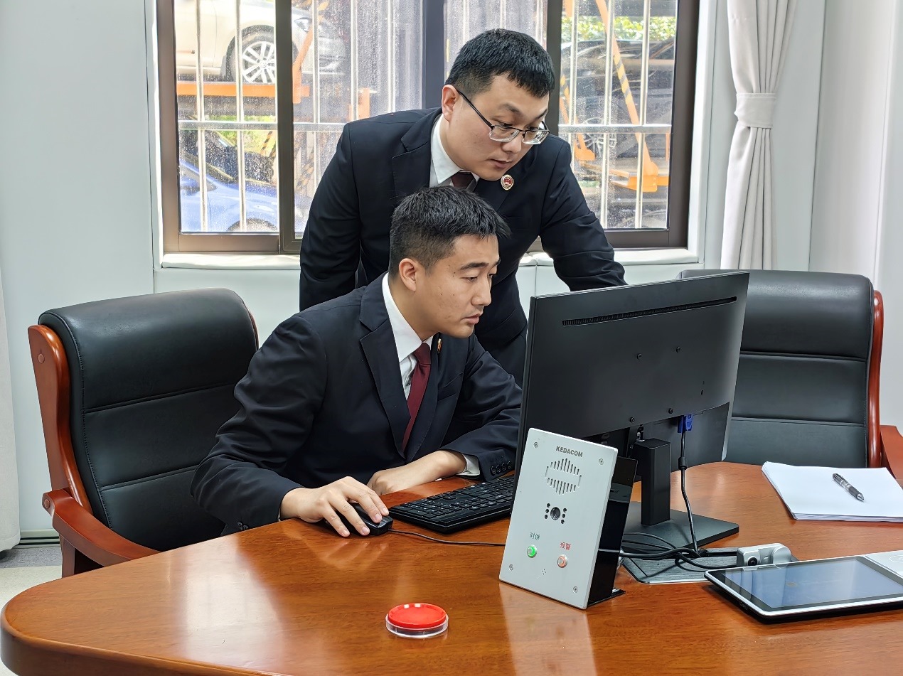 葉涵（左）和同事就一起電信網(wǎng)絡詐騙案件研討分析案情（記者彭照 攝）