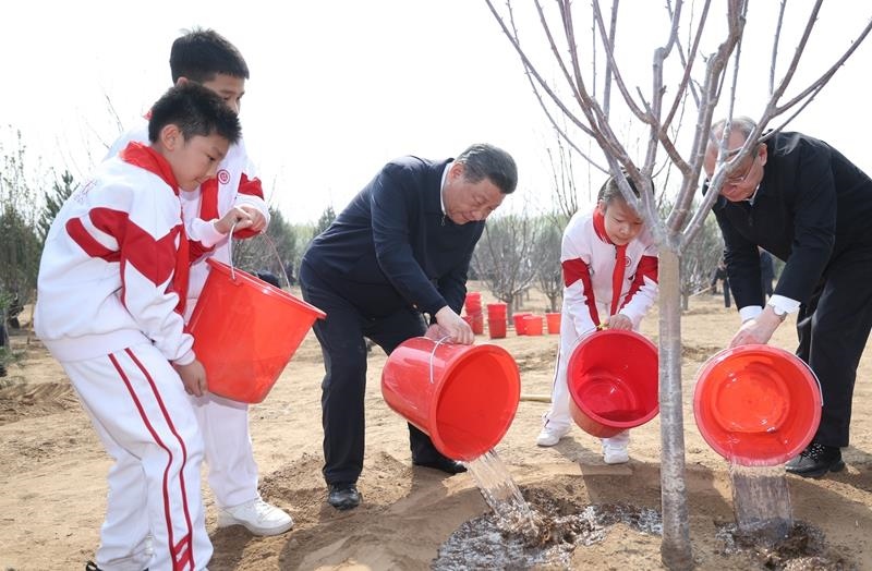 2024年4月3日，習(xí)近平總書記同少先隊(duì)員一起給剛栽下的樹苗澆水。