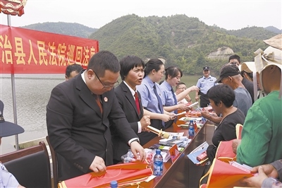 法院干警及相關(guān)部門工作人員對群眾進(jìn)行生態(tài)環(huán)境保護(hù)普法教育。