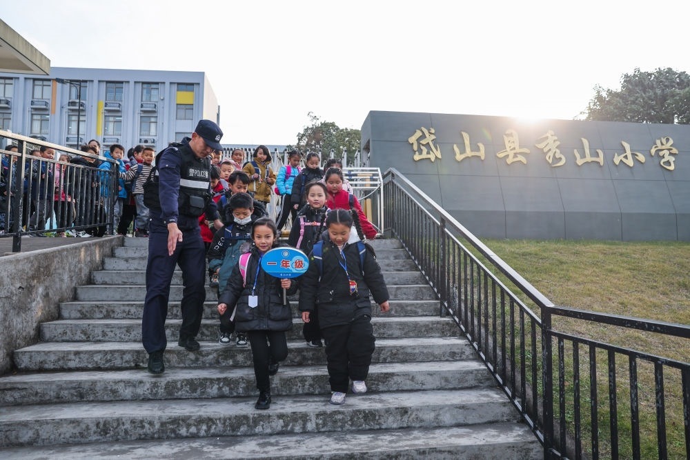 2023年12月20日，秀山派出所民警在秀山小學(xué)放學(xué)時(shí)間參與“護(hù)學(xué)崗”維持秩序，同時(shí)接獨(dú)自放學(xué)的學(xué)生去“民生小鋪”。浙江省舟山市岱山縣公安局秀山派出所聯(lián)合鄉(xiāng)鎮(zhèn)、社區(qū)成立“民生小鋪”，為當(dāng)?shù)鼐用?、外來?wù)工人員及其子女等服務(wù)，協(xié)助解決外來務(wù)工人員在工作、生活等方面的矛盾和問題，助力鄉(xiāng)鎮(zhèn)基層治理。新華社記者 徐昱 攝