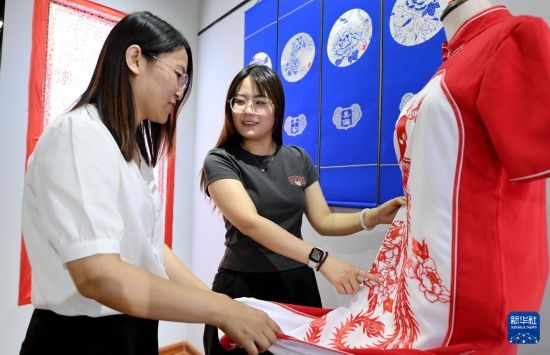 5月31日，在衡水市阜城縣一家剪紙工作室，游客在觀賞帶有剪紙?jiān)氐钠炫邸? width=