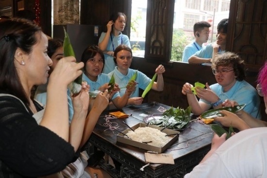 6月9日，美國青年代表在重慶永川松溉古鎮(zhèn)體驗(yàn)包粽子。新華社記者 周思宇 攝