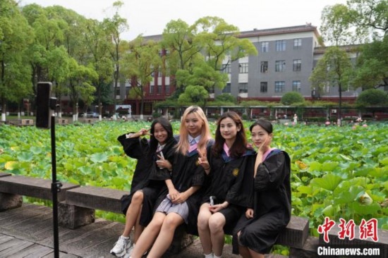 6月19日，時(shí)值一年畢業(yè)季，四川大學(xué)望江校區(qū)荷花池里的荷花盛開，成為了畢業(yè)生們的打卡圣地，吸引了眾多畢業(yè)生拍照留念。圖為畢業(yè)生在荷花池邊拍照留念。中新社記者 安源 攝
