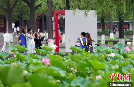 6月19日，時(shí)值一年畢業(yè)季，四川大學(xué)望江校區(qū)荷花池里的荷花盛開，成為了畢業(yè)生們的打卡圣地，吸引了眾多畢業(yè)生拍照留念。圖為畢業(yè)生在荷花池邊拍照留念。中新社記者 安源 攝