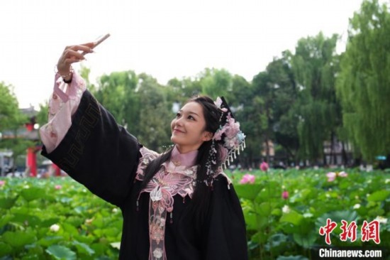 6月19日，時(shí)值一年畢業(yè)季，四川大學(xué)望江校區(qū)荷花池里的荷花盛開，成為了畢業(yè)生們的打卡圣地，吸引了眾多畢業(yè)生拍照留念。圖為畢業(yè)生在荷花池邊拍照留念。中新社記者 安源 攝