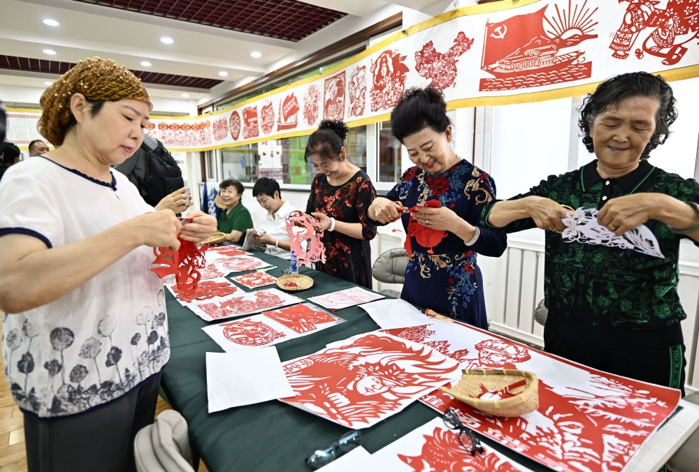 6月19日，長城花園社區(qū)居民在社區(qū)“才藝堂”制作剪紙。