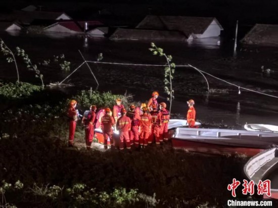  7月6日凌晨3時，在湖南岳陽華容縣團洲垸洞庭湖一線堤防，救援人員剛剛完成一次救援任務，遠處是被淹的民房。中新社記者 白祖偕 攝