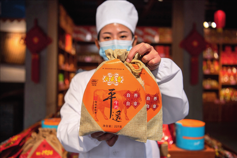 在位于山西省晉中市平遙縣的平遙古城南大街的一家平遙牛肉店內(nèi)，工作人員展示一款牛肉產(chǎn)品（資料照片）楊晨光攝 / 本刊