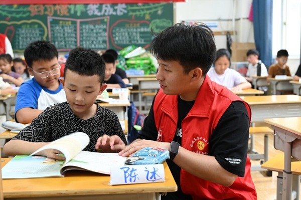 鄭州市二七區(qū)暑托班的志愿者輔導孩子寫作業(yè)。人民網記者王玉興攝
