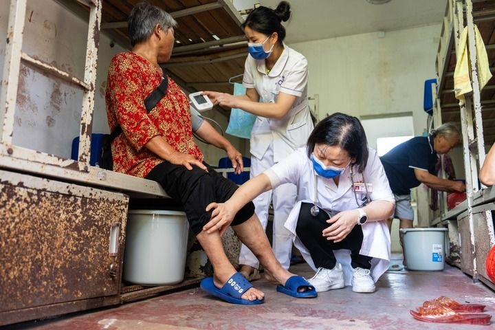2024年7月30日，在湖南省湘潭縣河口中學(xué)安置點，醫(yī)務(wù)人員為受洪水影響而轉(zhuǎn)移安置的群眾檢查身體。 新華社記者 陳思汗 攝