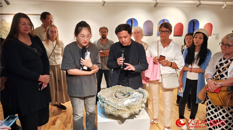 參展人、景德鎮(zhèn)陶瓷大學(xué)設(shè)計(jì)藝術(shù)學(xué)院副院長(zhǎng)余劍峰（中）向來(lái)賓介紹參展作品。人民網(wǎng)記者 殷淼攝