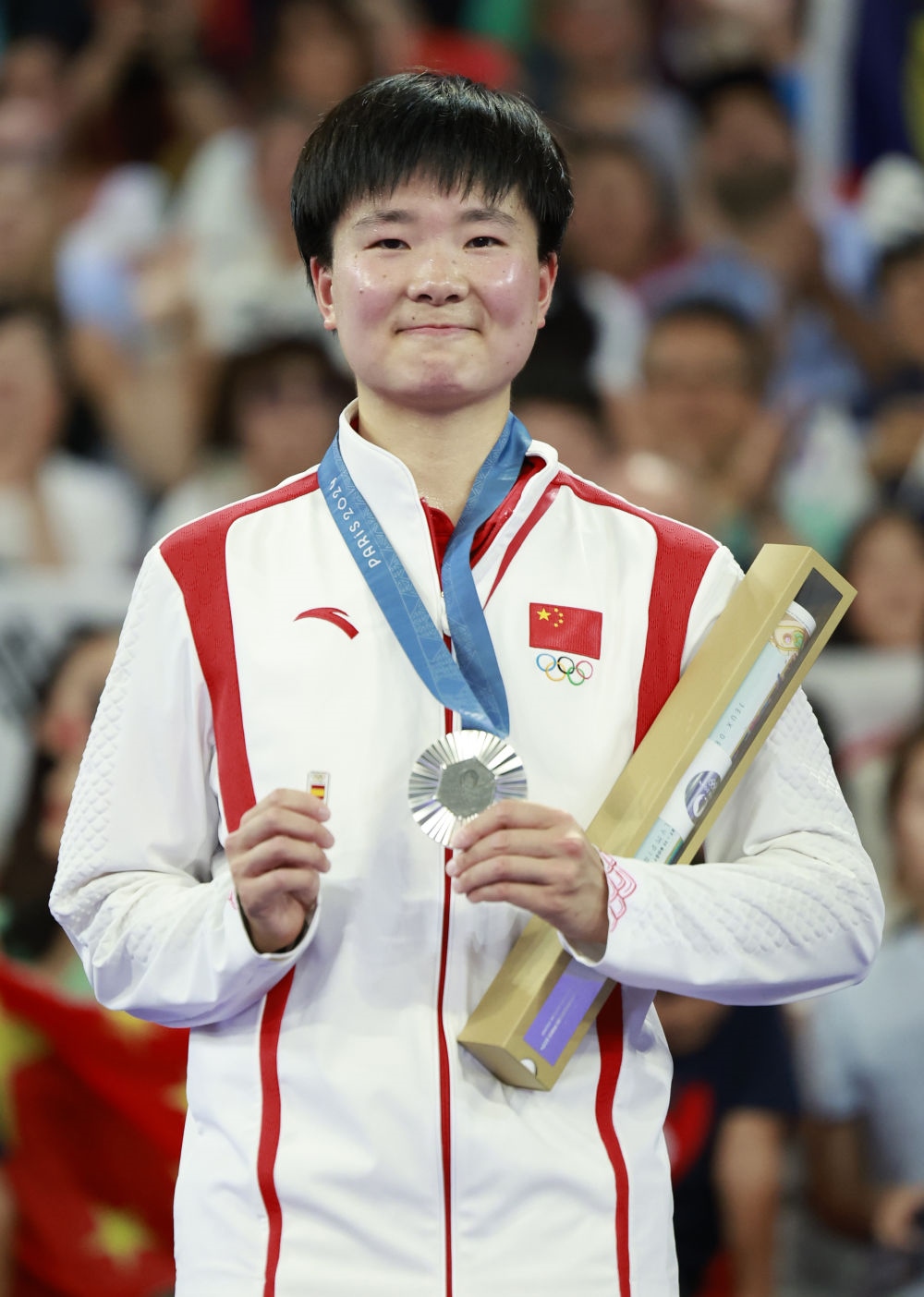 巴黎奧運(yùn)會(huì)羽毛球女子單打亞軍、中國(guó)選手何冰嬌在頒獎(jiǎng)儀式上一手握著銀牌，一手握著西班牙奧委會(huì)徽章（2024年8月5日攝）。新華社記者 任正來(lái) 攝