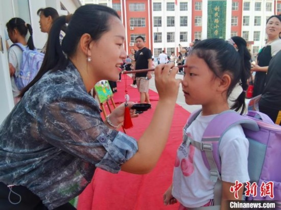 圖為衡水市利民路小學(xué)，老師為學(xué)生點(diǎn)朱砂痣，寓意開啟智慧。張松 攝